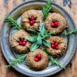 A serving platter with mini bundt chestnut roasts surrounded by fresh herbs and cranberries.
