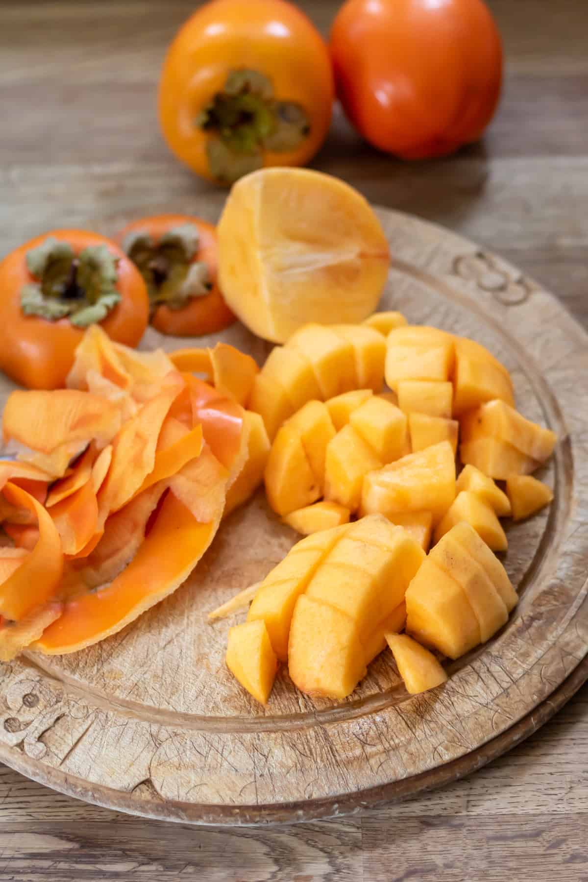 Peeled and chopped persimmons on a wooden cutting board.