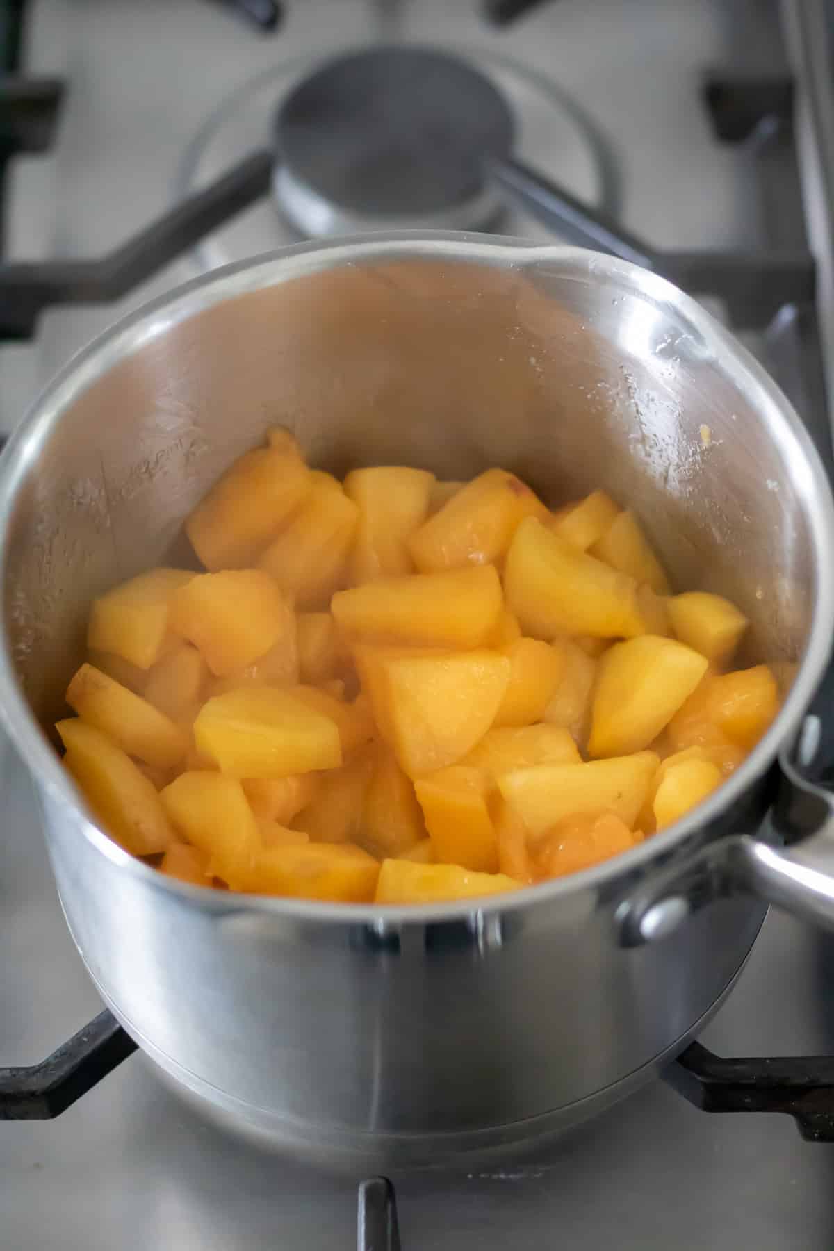Cooked persimmon compote in a pot on the stovetop.
