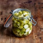 A wooden table with a glass jar of quick pickled brussels sprouts.