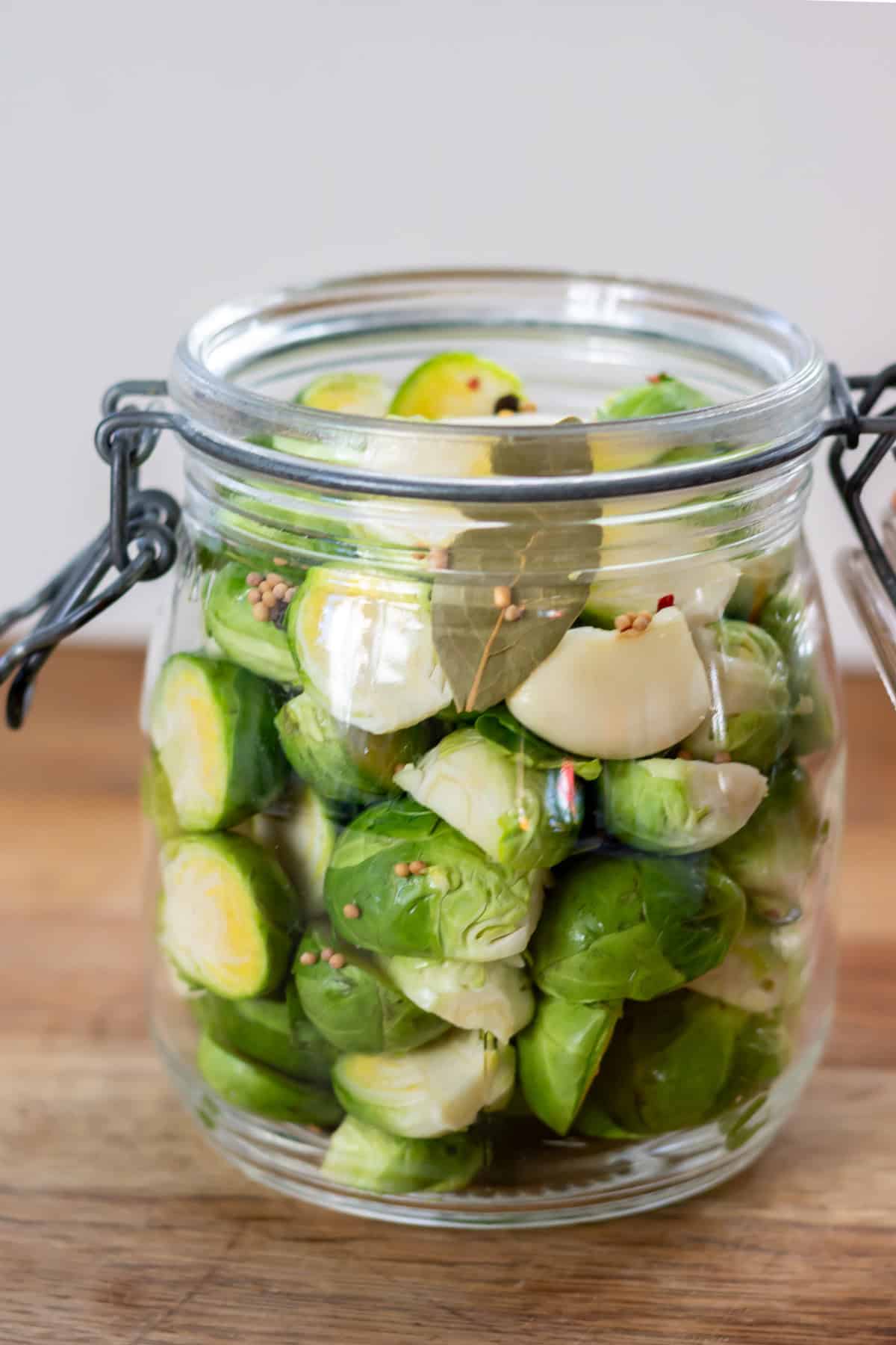 Packing the sprouts, bay leaf and spices into the jar.