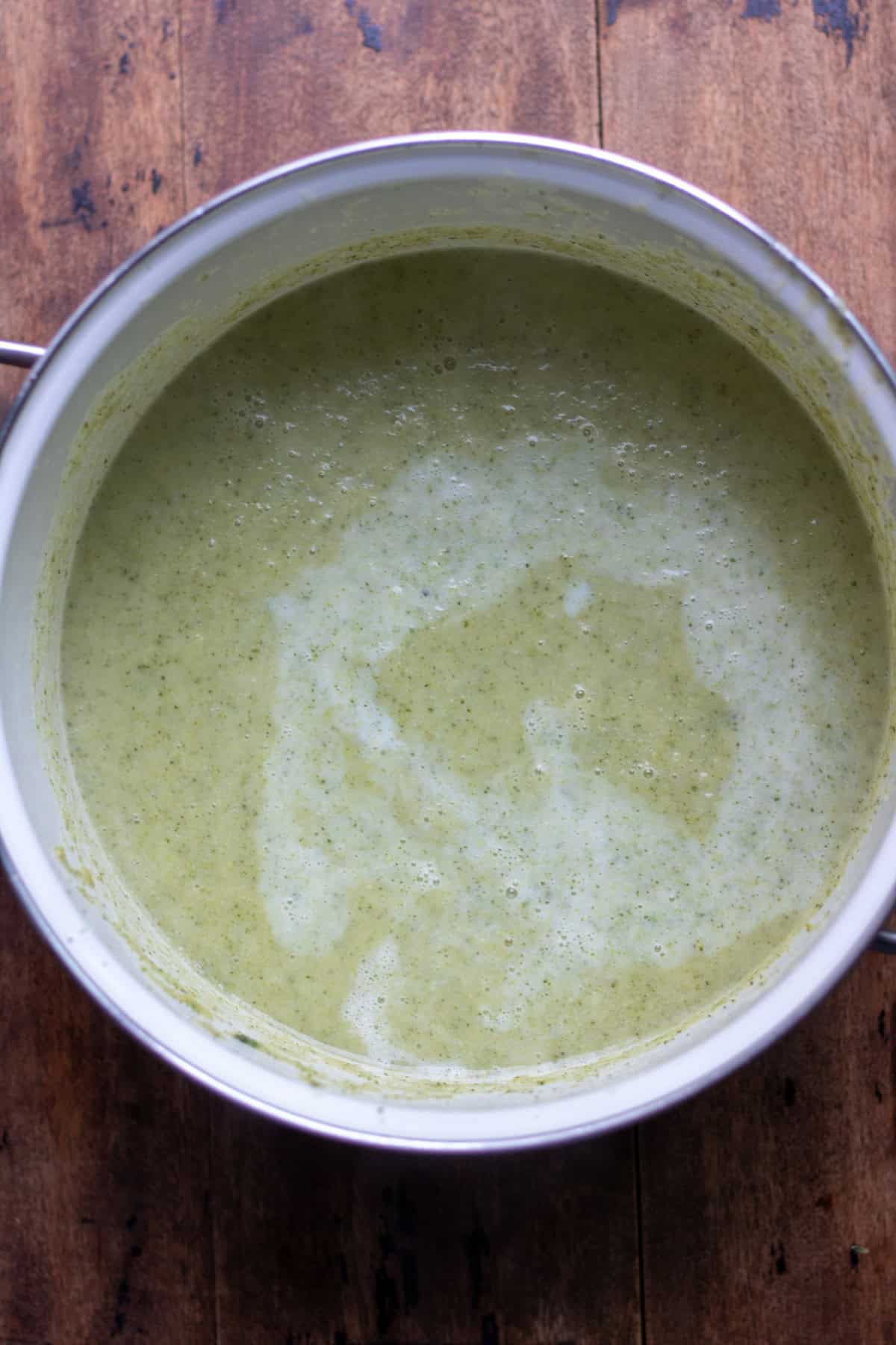Stirring the milk into the blended broccoli soup.
