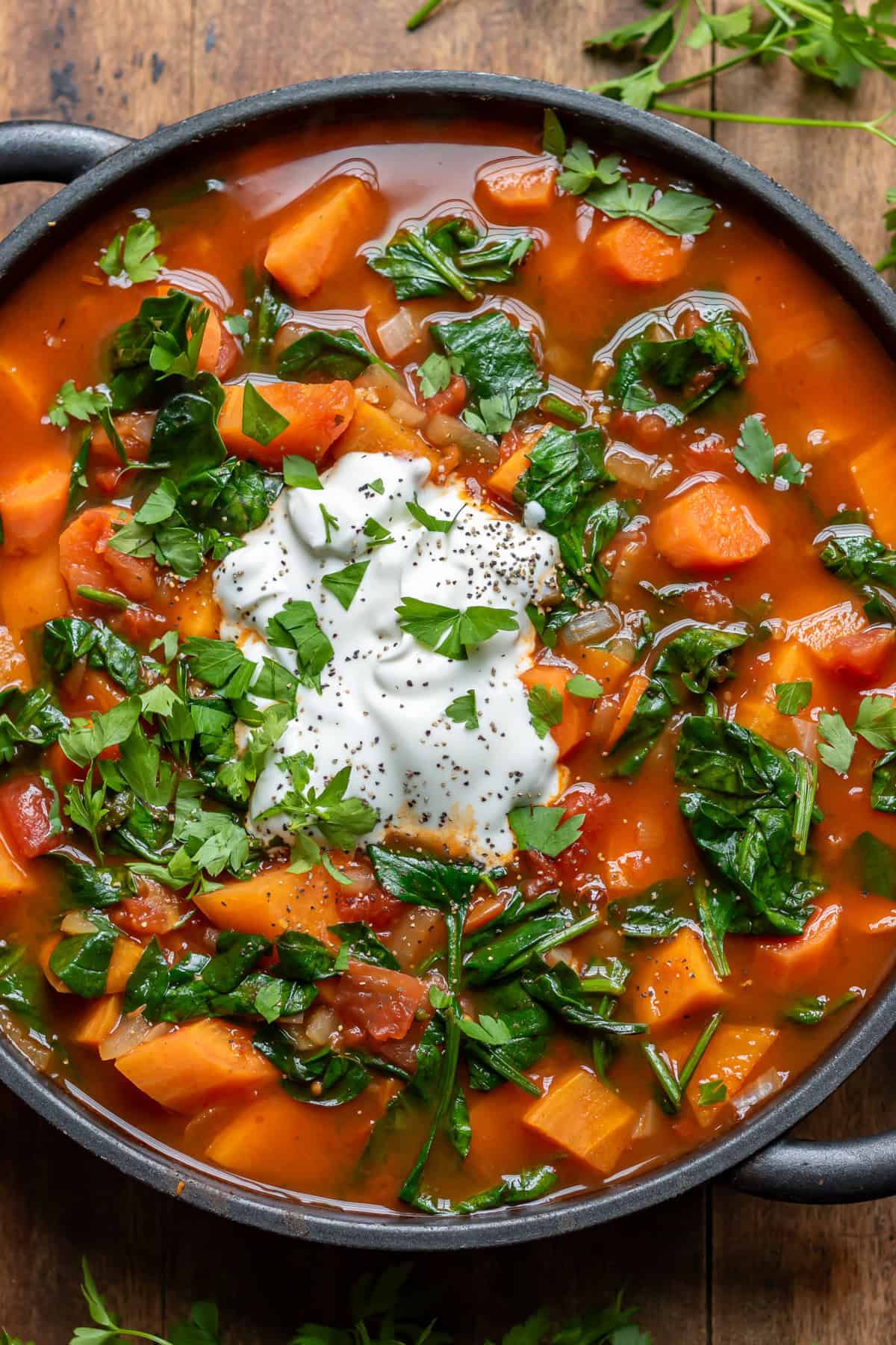Serving dish of chipotle sweet potato soup with a dollop of yogurt and sprinkled with herbs.