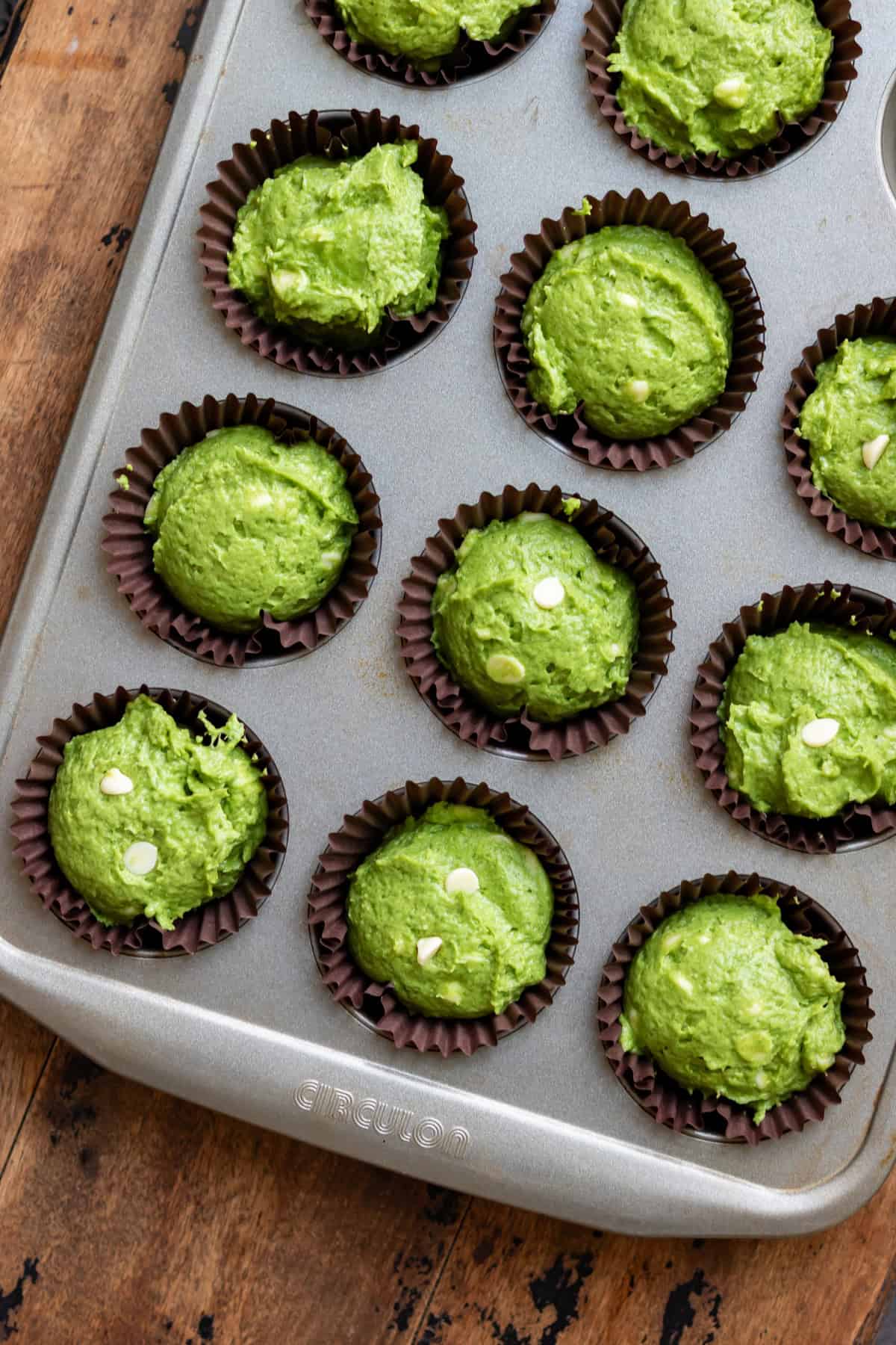 Muffin batter added to muffin cups in a pan.