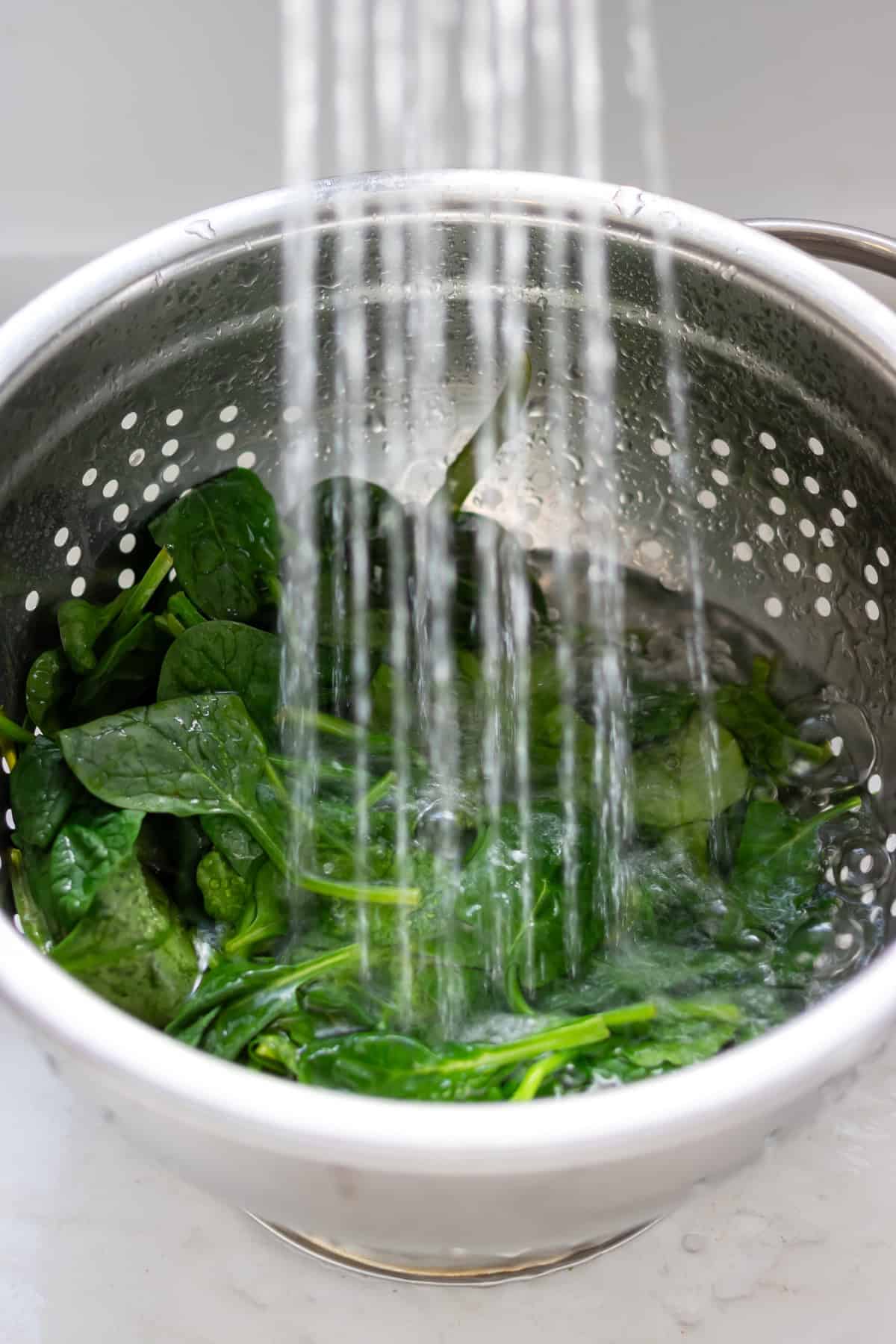 Rinsing the spinach in a colander.