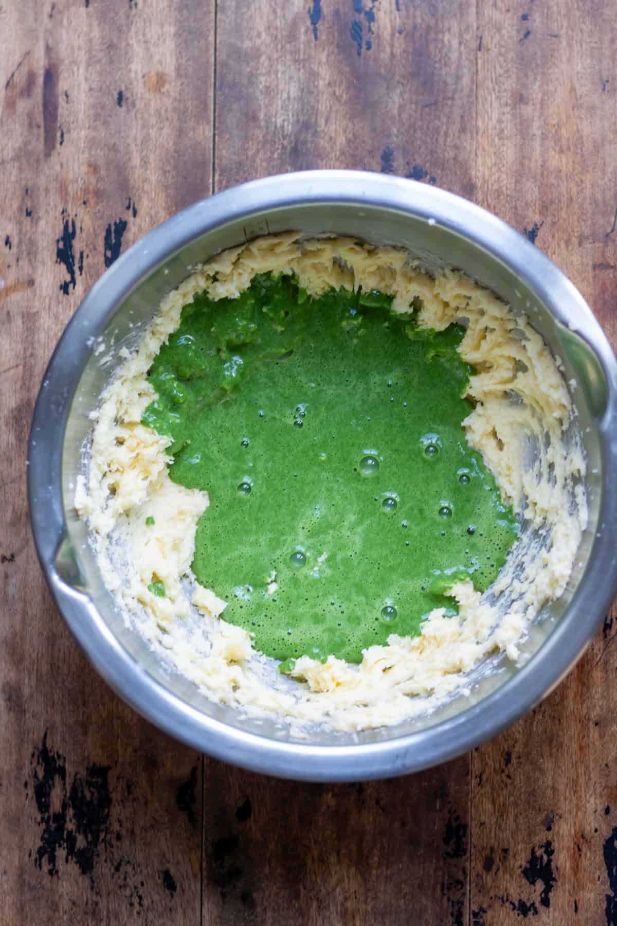 Spinach puree added to the mixing bowl of creamed butter and sugar.