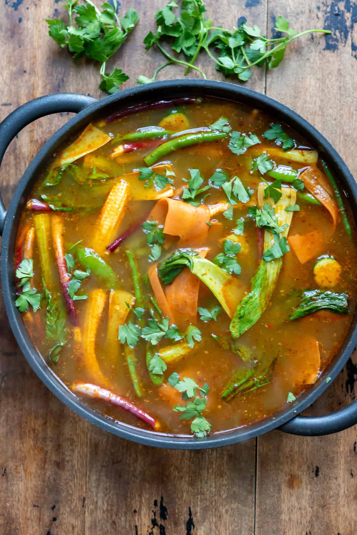 A serving dish of the thai vegetable soup broth.