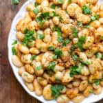 Close up of a plate of garlic butter beans topped with fresh parsley.