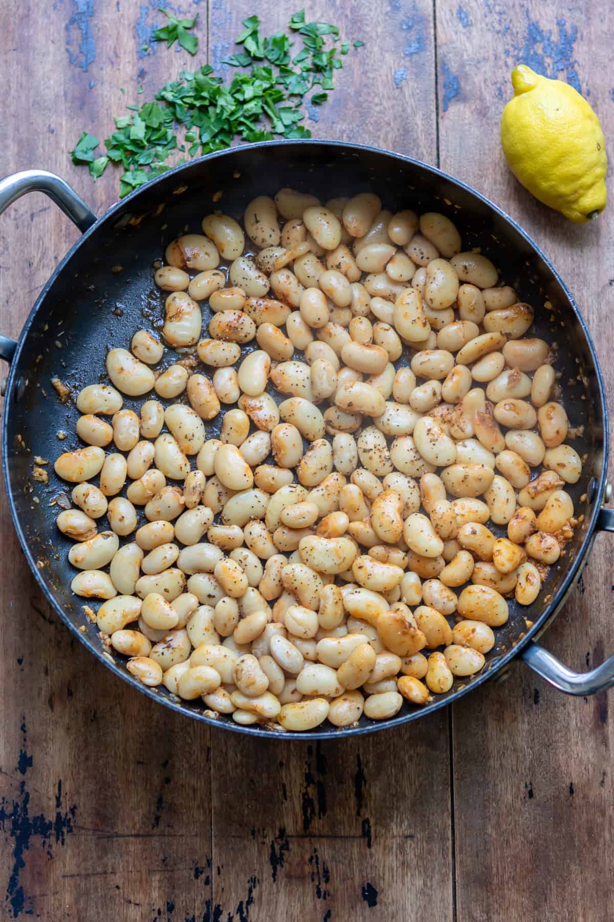 Cooked smoky garlic butter beans in a pan.