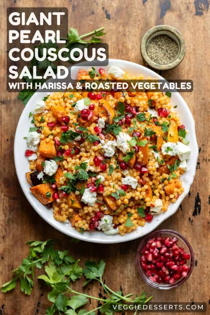Serving dish of salad on a table, with text: Giant Pearl Couscous Salad with Harissa and Roasted Vegetables.