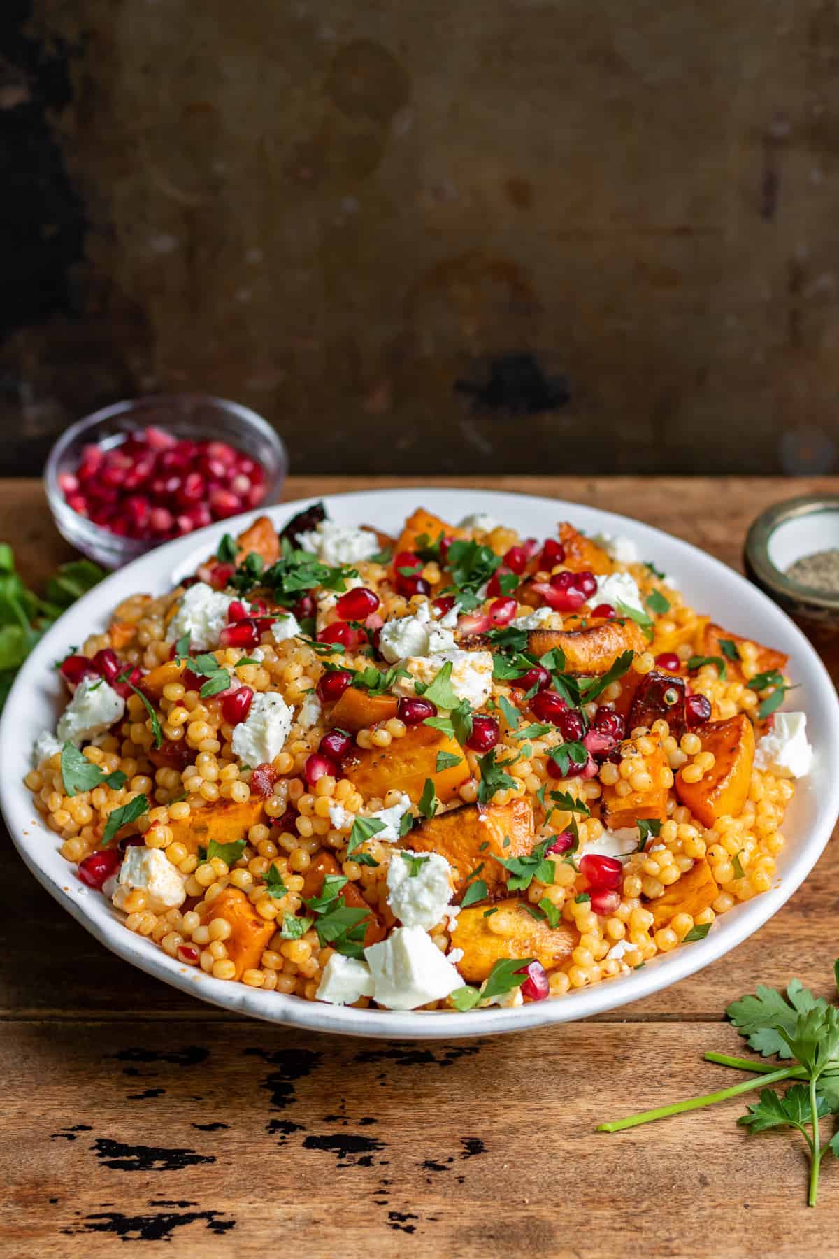 Side view of a bowl of pearl couscous salad with roasted vegetables.
