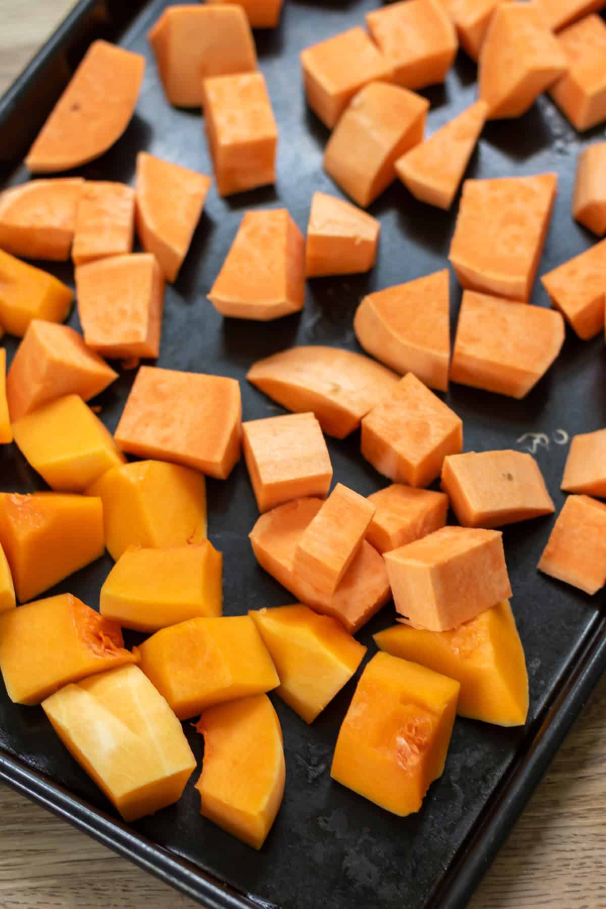 Squash and sweet potato cubes on a baking sheet.