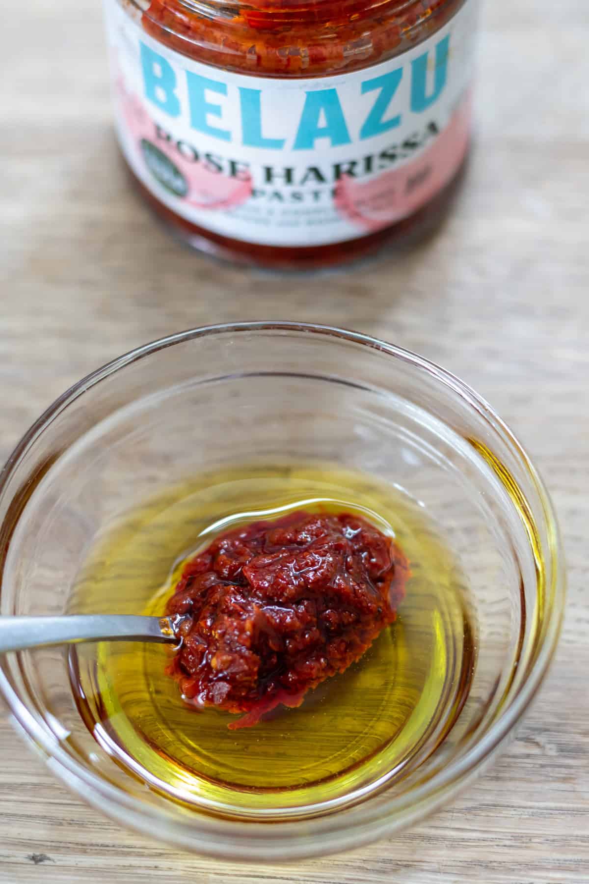 Stirring a spoonful of rose harissa into extra virgin olive oil.