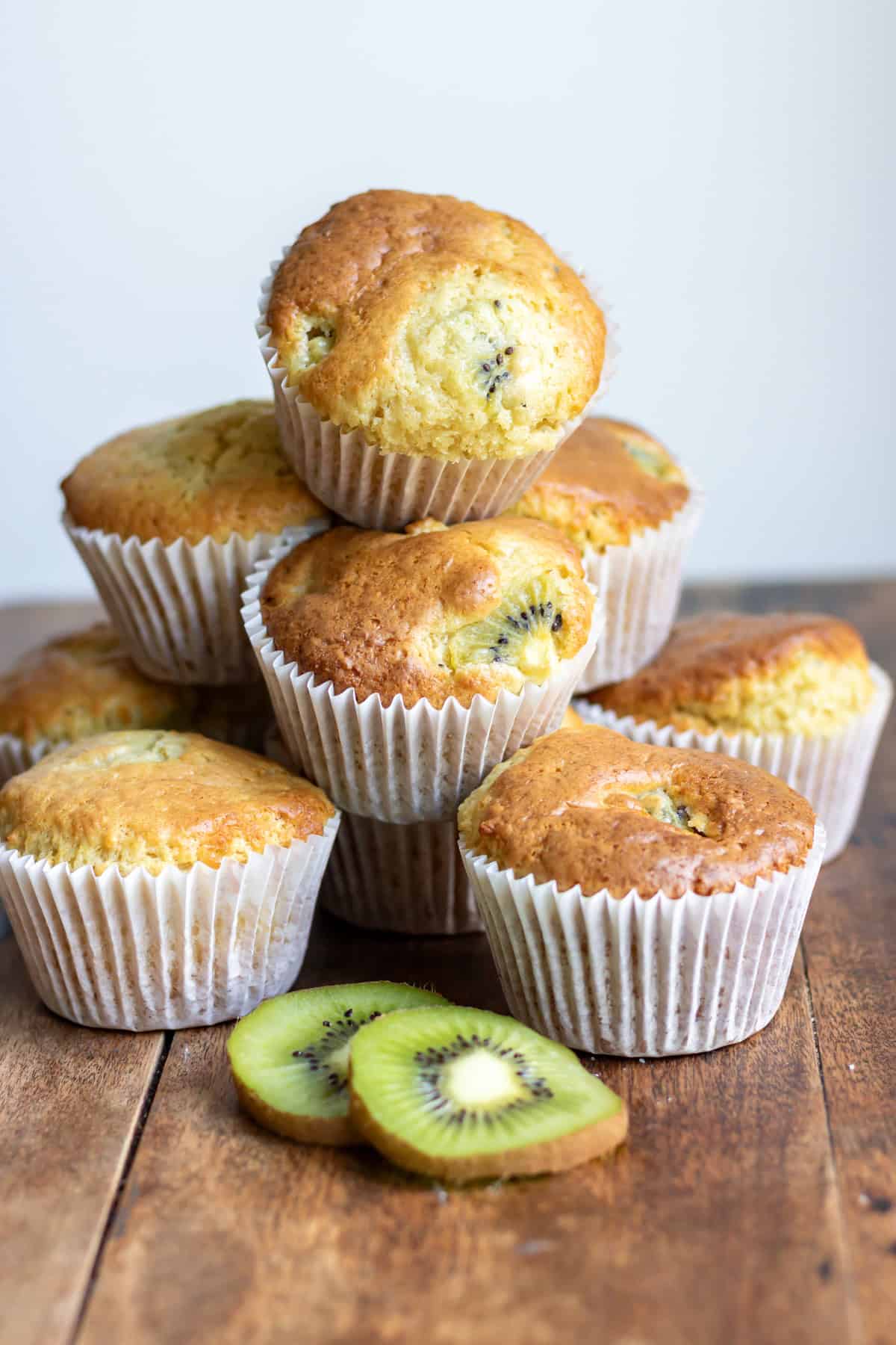 A table with kiwi muffins on it, next to slices of fresh kiwi.