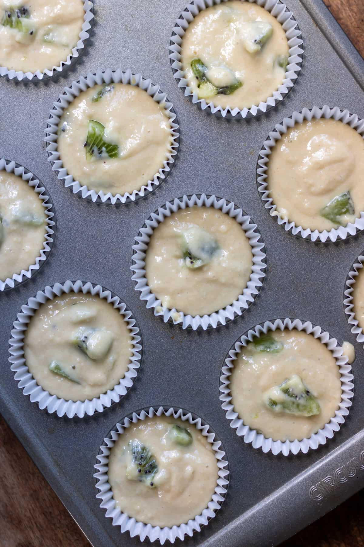 Kiwi muffin batter in the muffin pan.