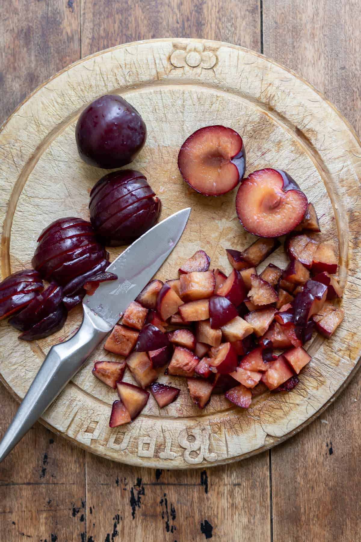 Chopped and sliced plums on a chopping board.