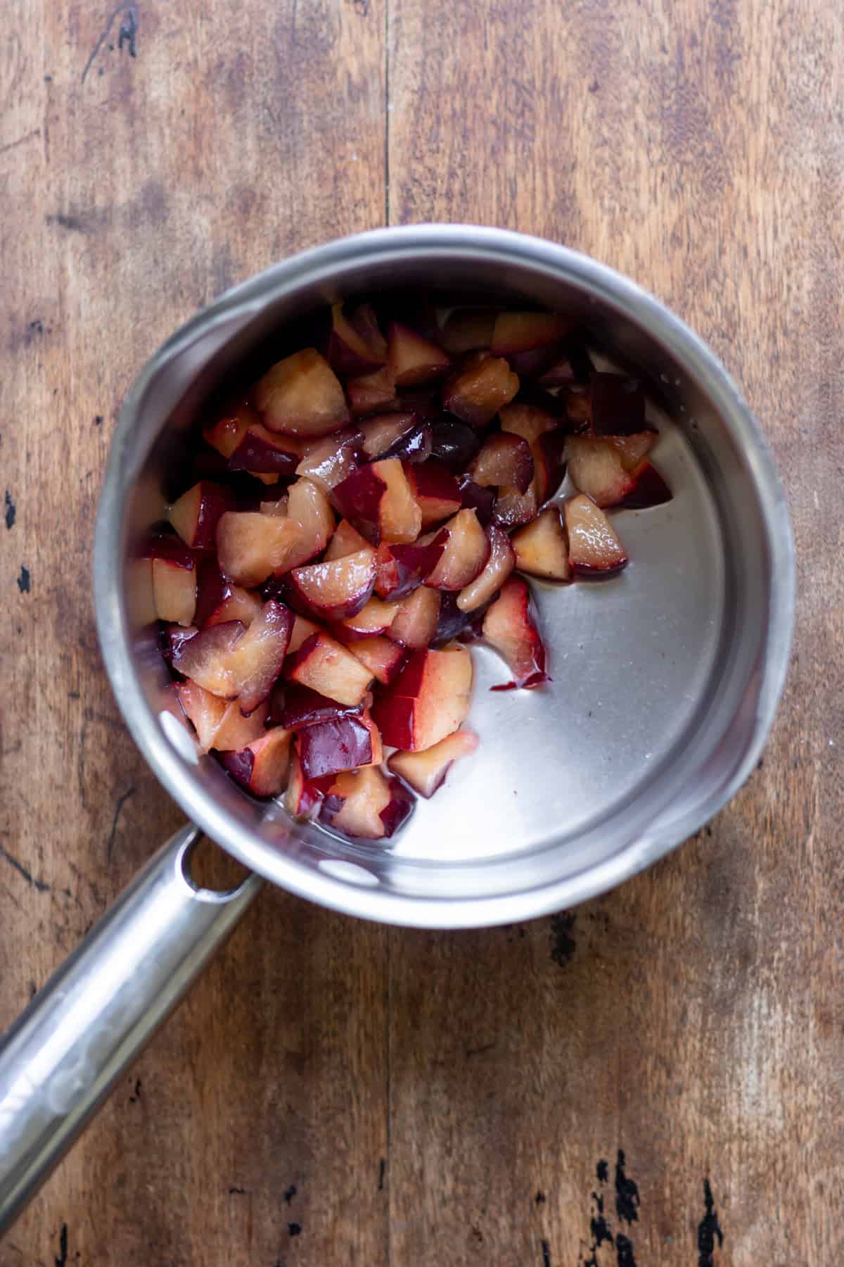 Chopped plums in a saucepan with vanilla, sugar and water.
