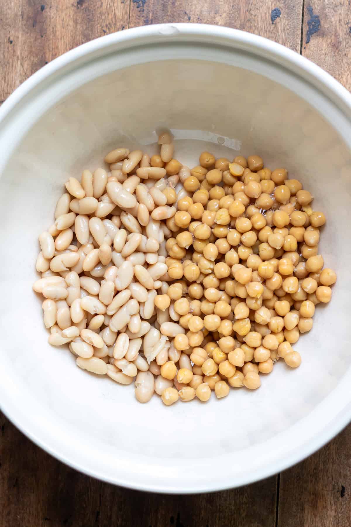 A mixing bowl with chickpeas and canellini beans.