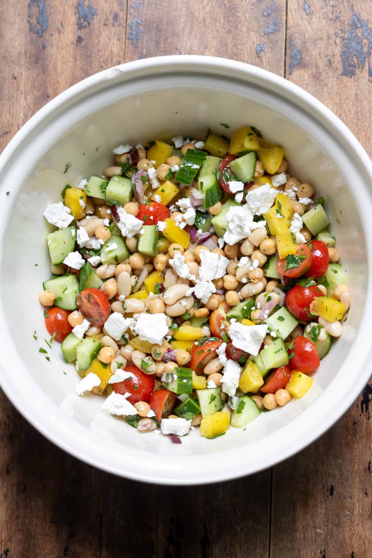 Crumbled feta added to the bowl of bean salad.