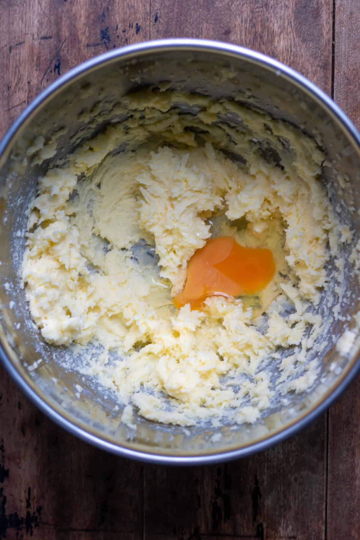 Butter and sugar creamed together in a mixing bowl, with an egg added.