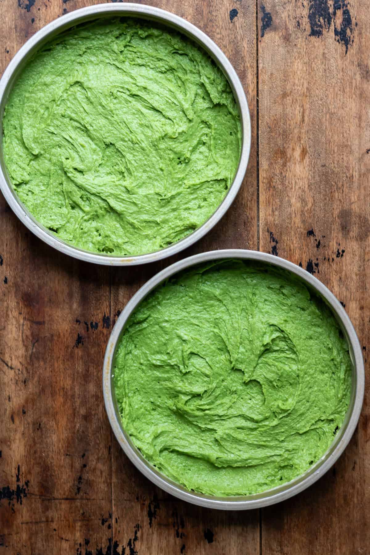 Stinging nettle cake batter divided into two round baking pans.