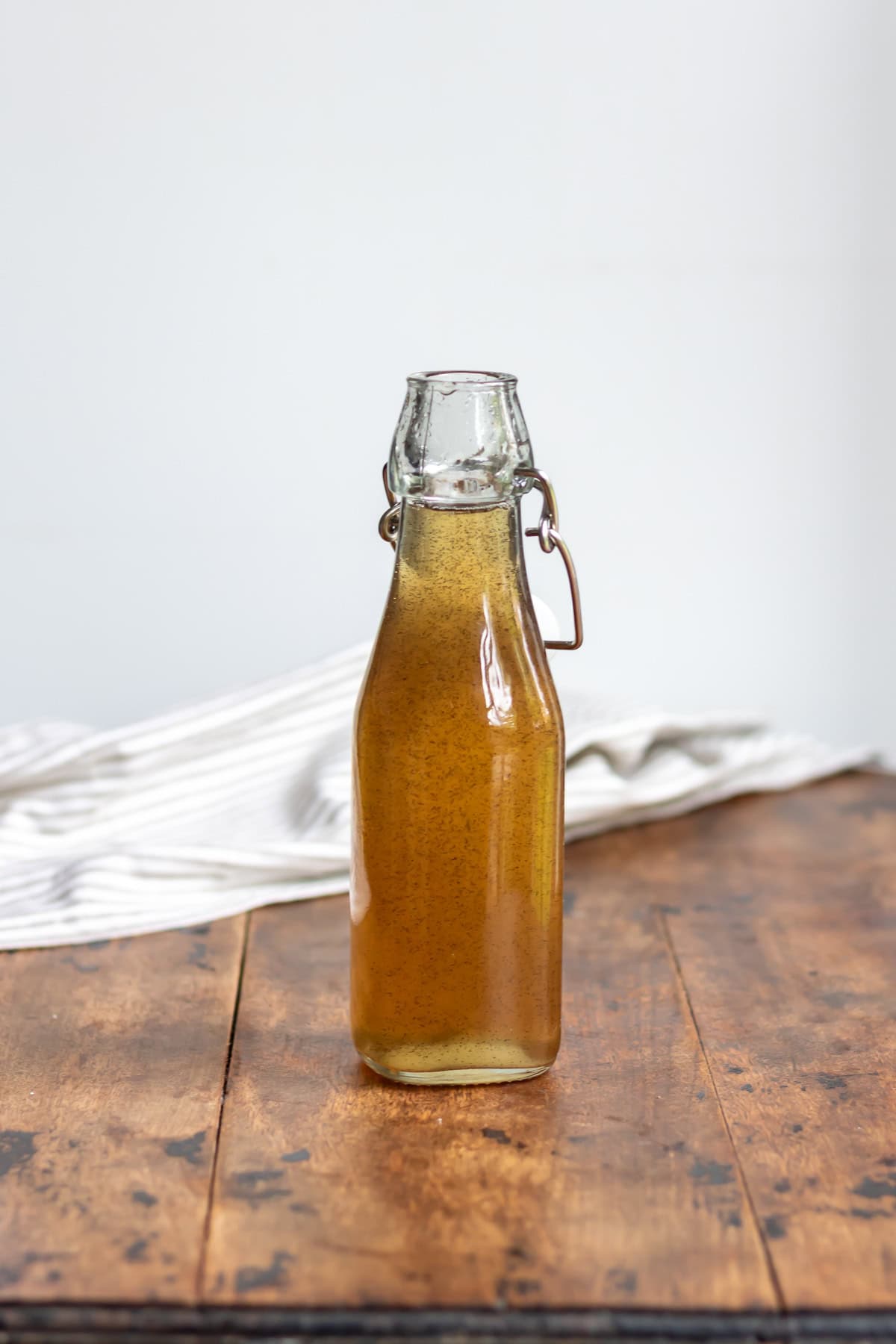 Wooden table with a glass bottle of vanilla syrup.