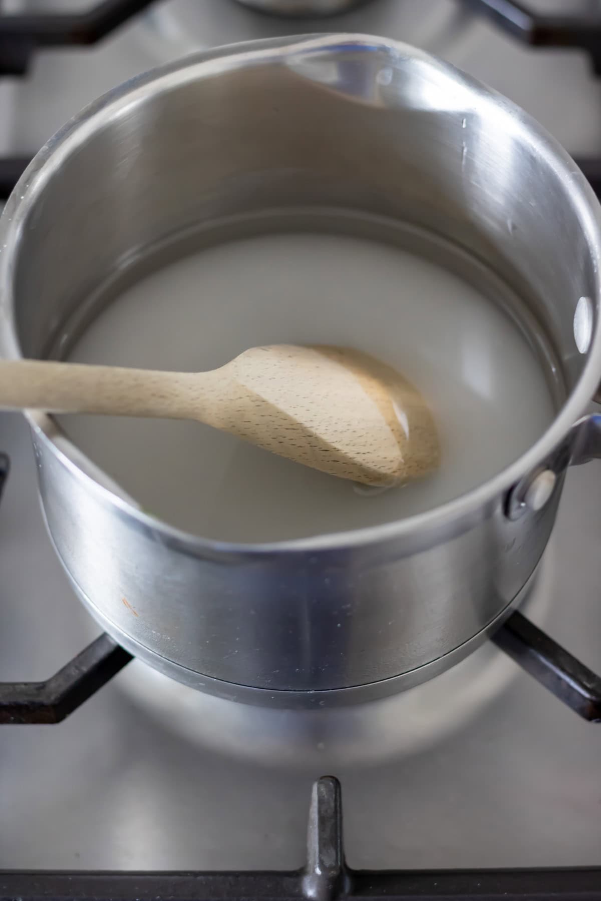 Stirring the sugar and water in a small pot.