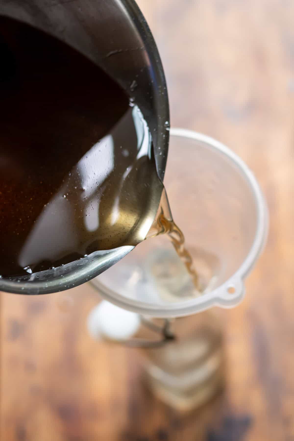 Pouring the cooled vanilla syrup into a bottle with a funnel.