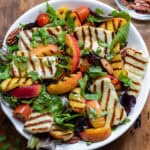 A serving dish of hot honey grilled halloumi peach salad.