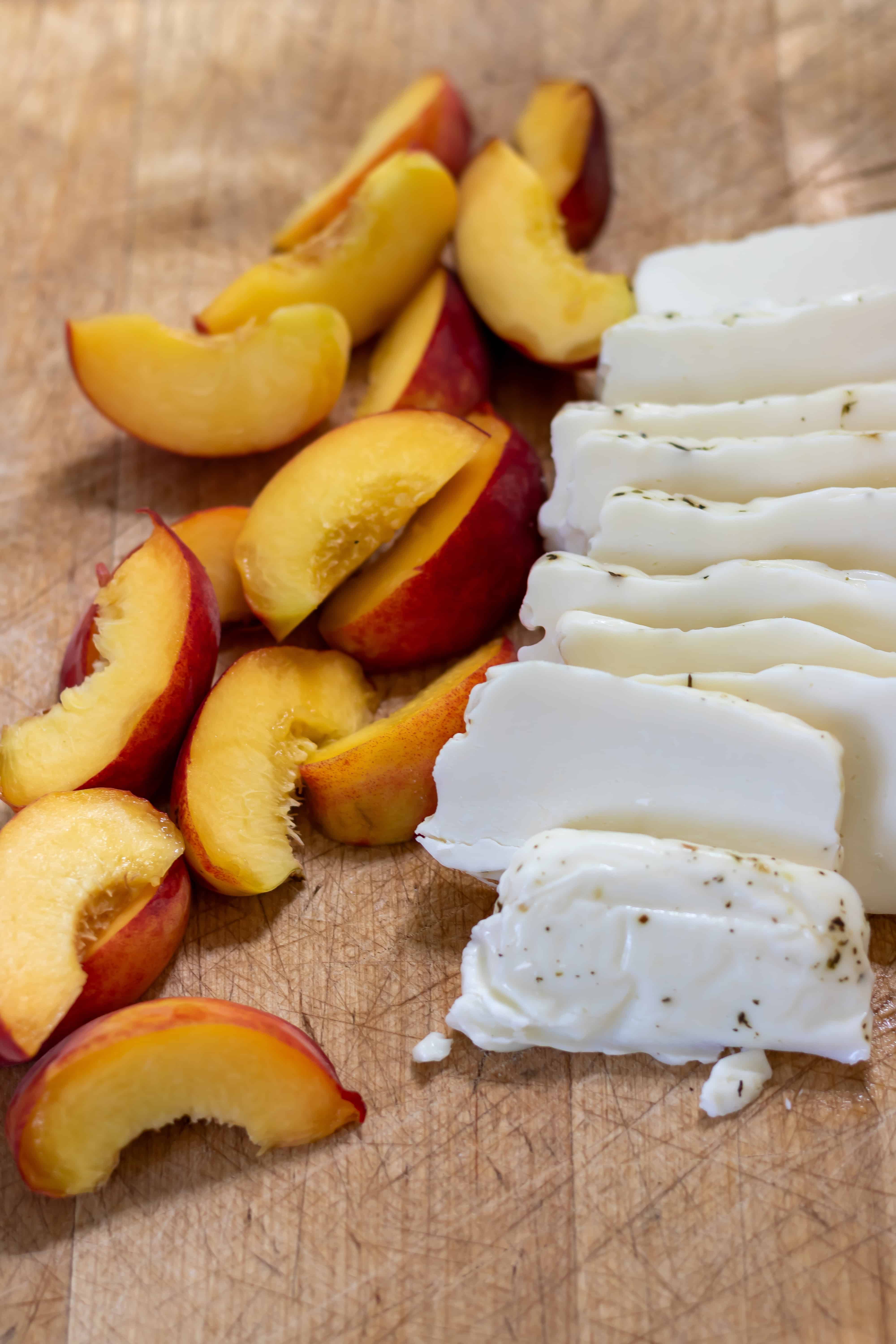 Sliced peaches and halloumi on a cutting board.