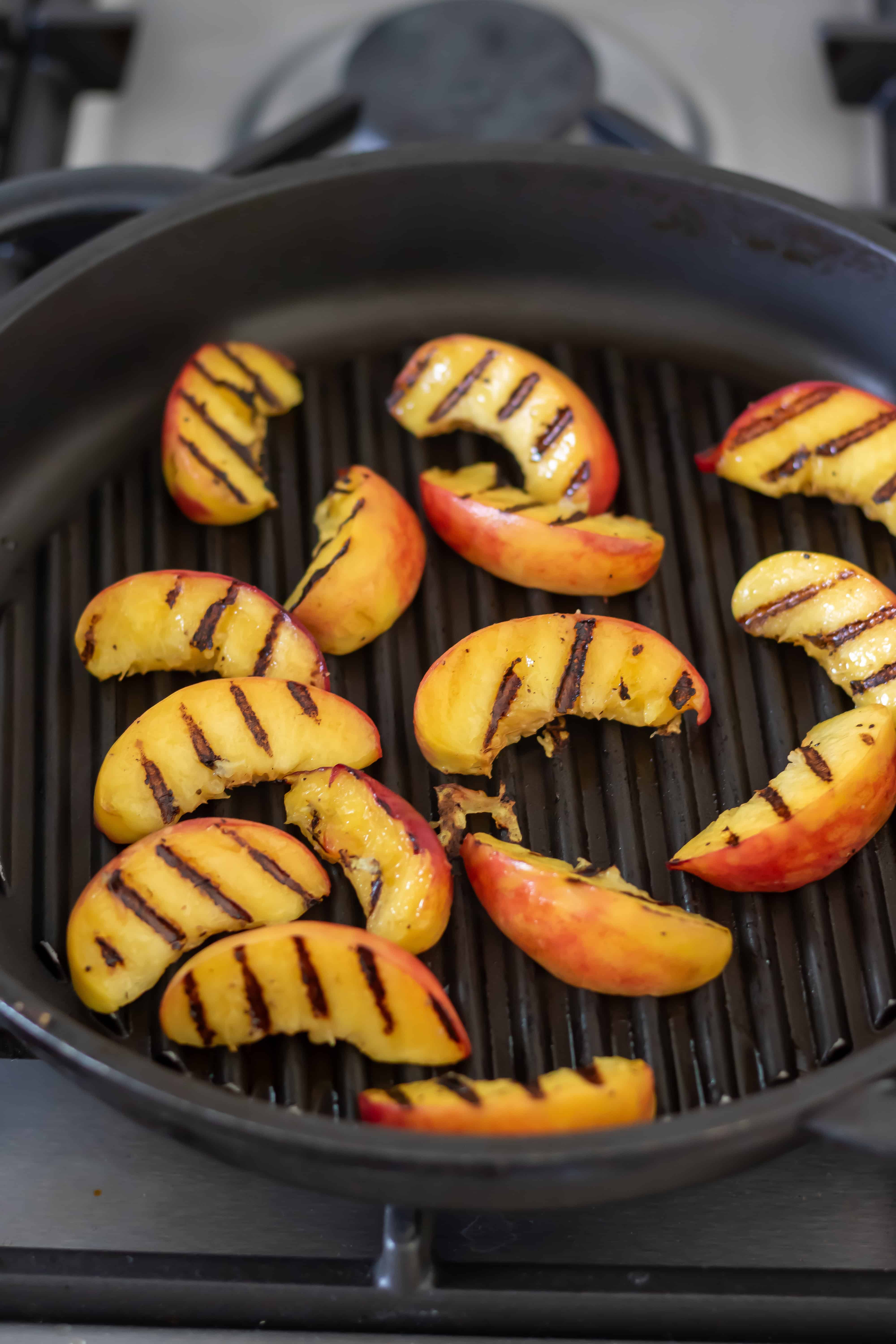 Cooking sliced peaches on a grill pan.