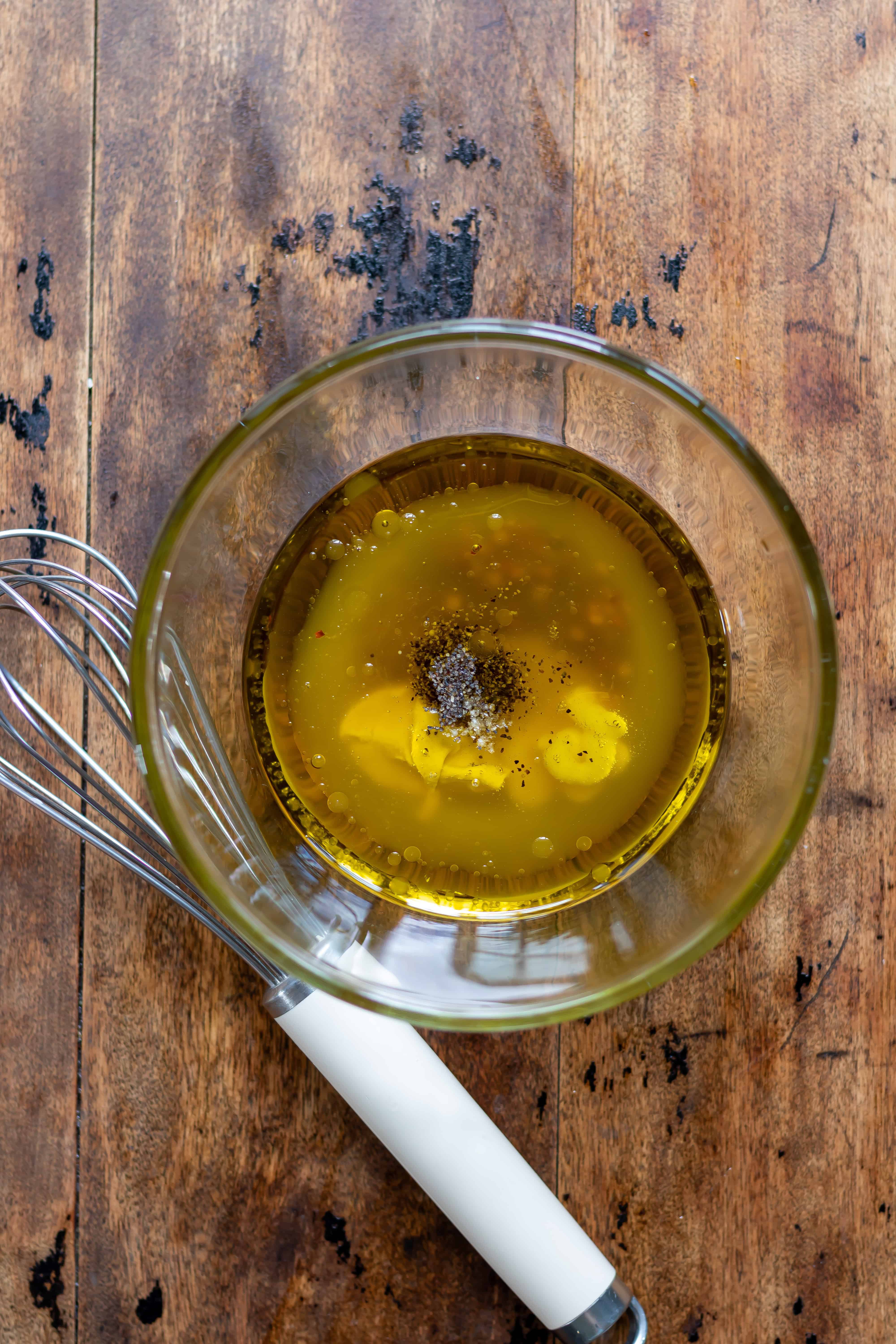 Hot honey vinaigrette salad dressing ingredients in a small bowl with a whisk next to it.