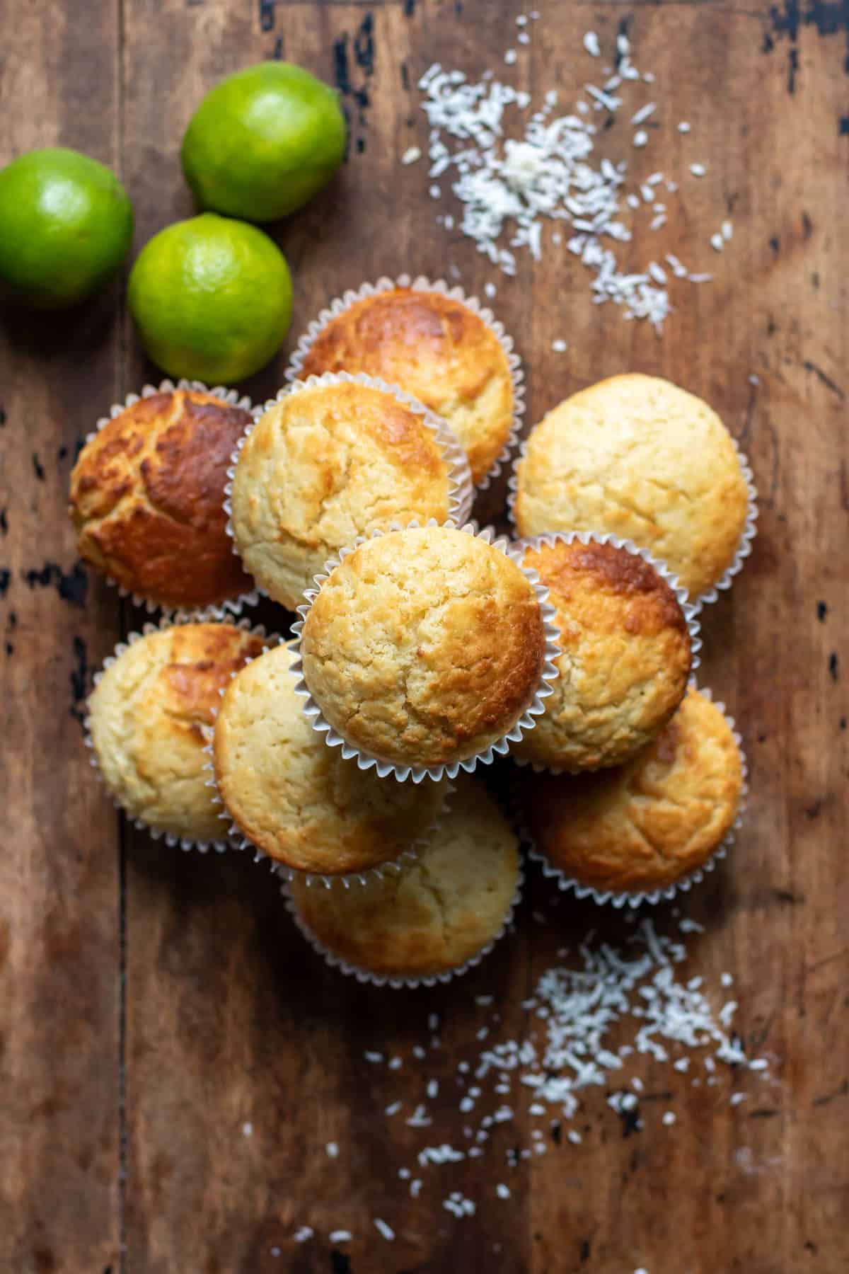 Looking down at a stack of lime coconut muffins on a wooden table.
