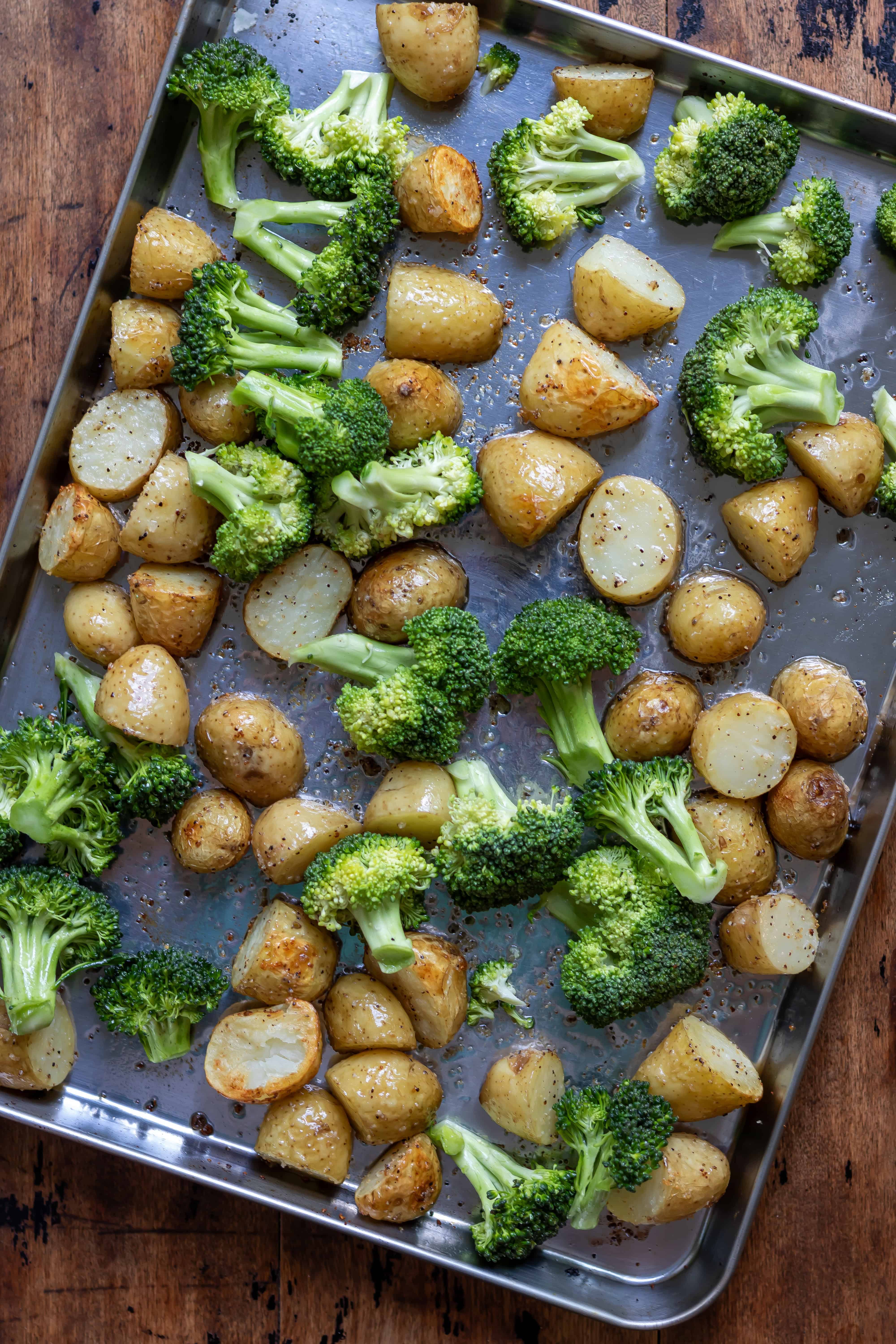 Broccoli added to the partially roasted potatoes on the baking sheet.