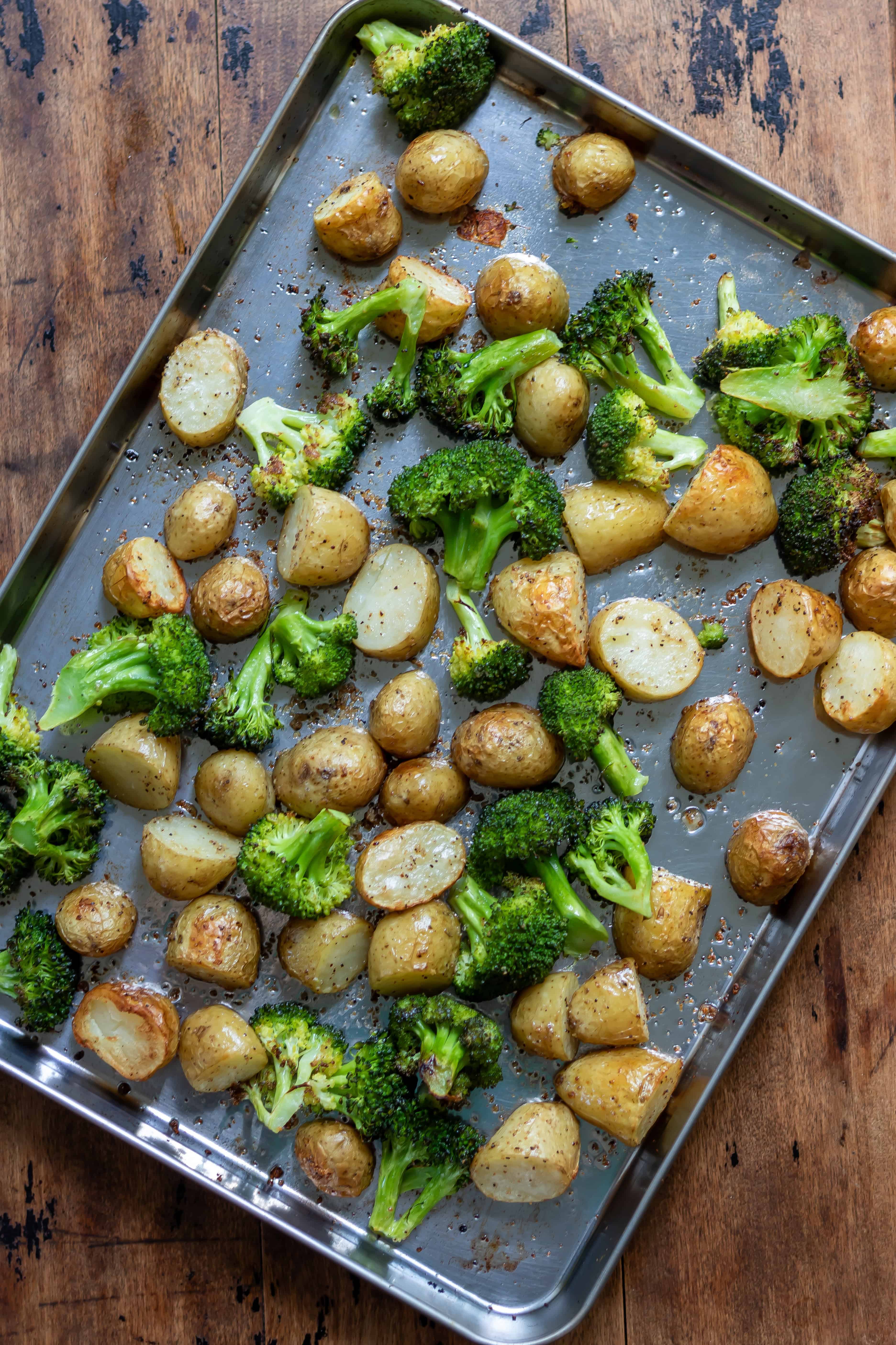 Roasted broccoli and potatoes on a baking sheet.