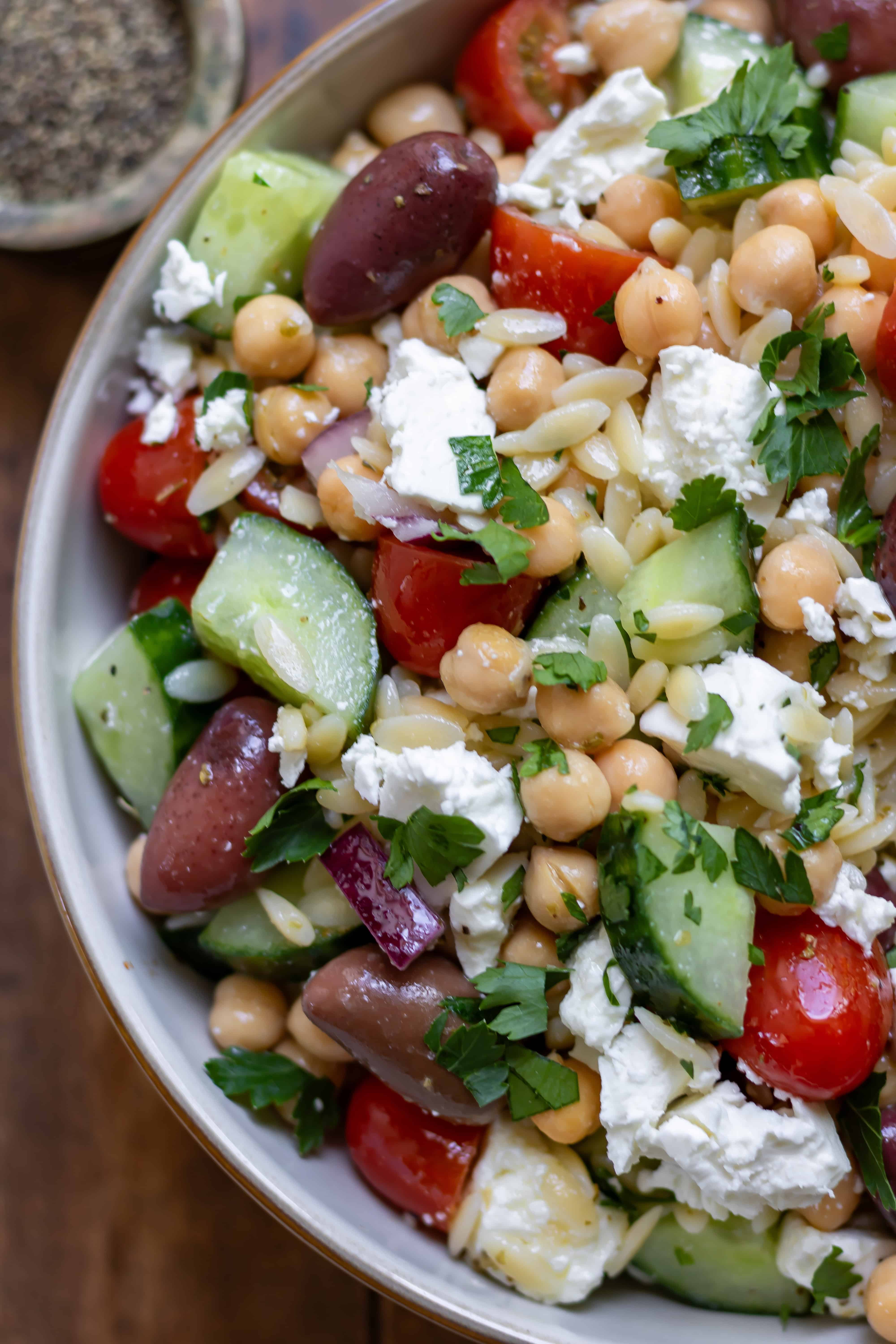Close up of Mediterranean Orzo Salad in a bowl, with kalamata olives and feta cheese.