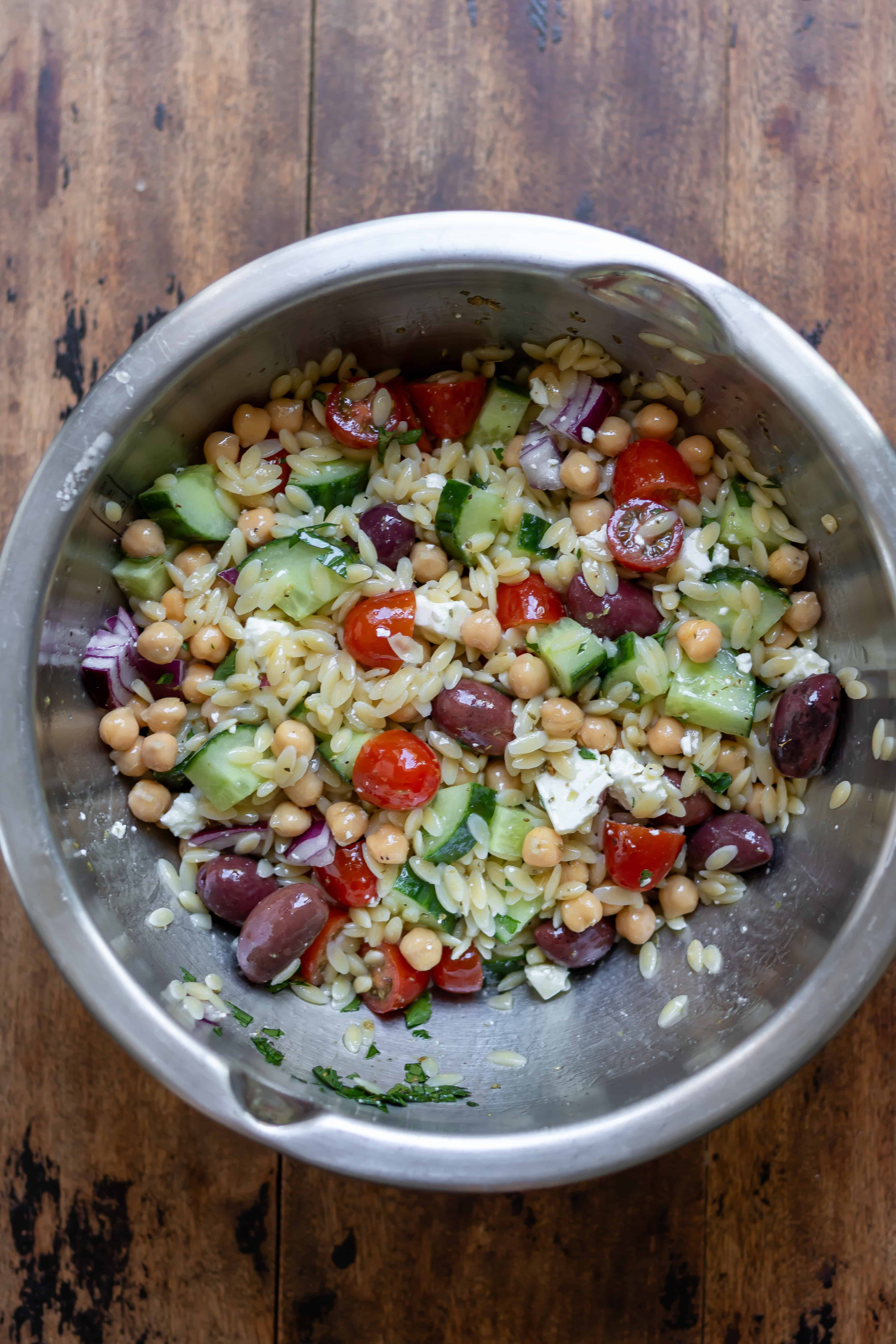 Mixed Mediterranean orzo salad in a mixing bowl.