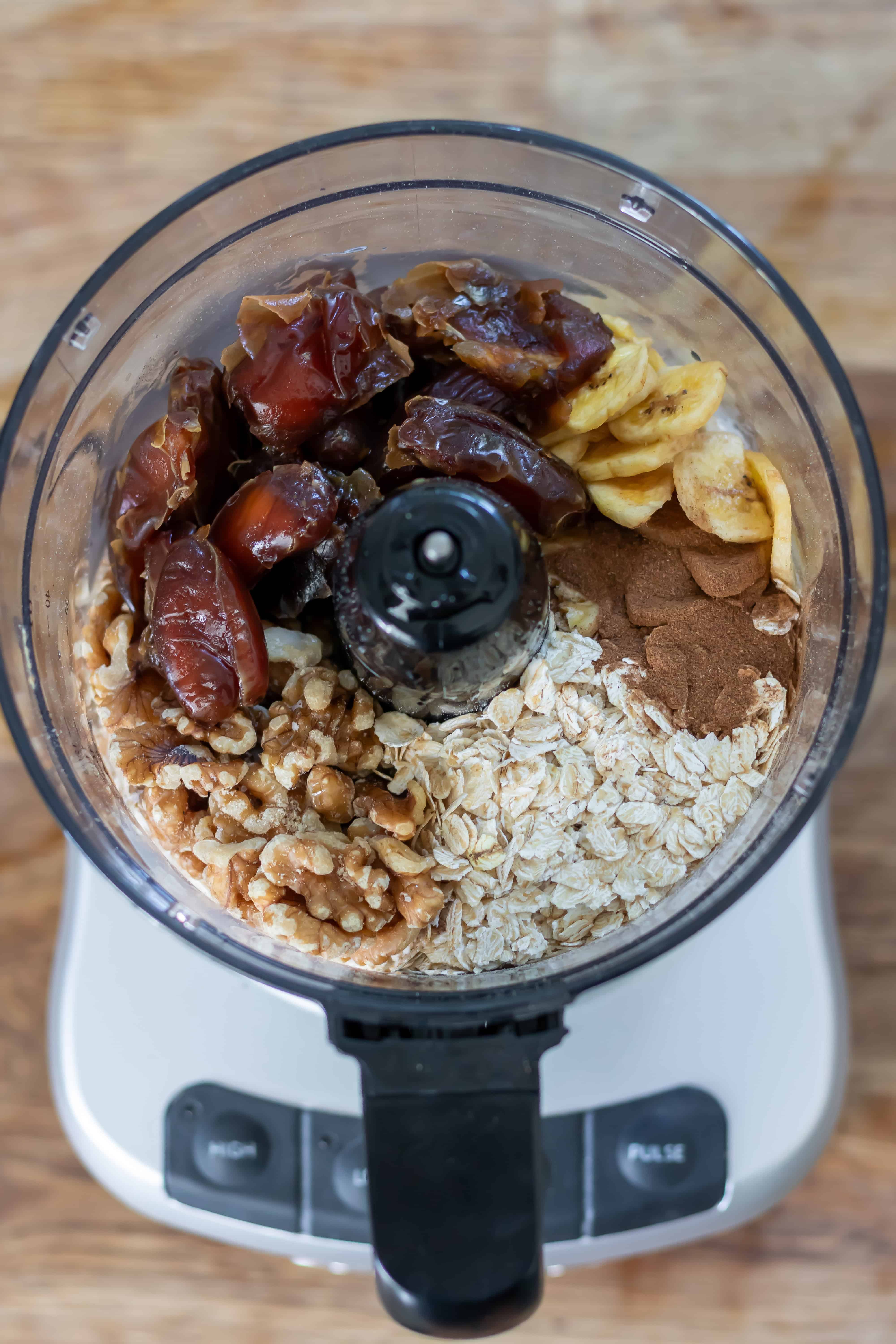 Dates, oats, walnuts, banana chips, vanilla and cinnamon in the bowl of a food processor.