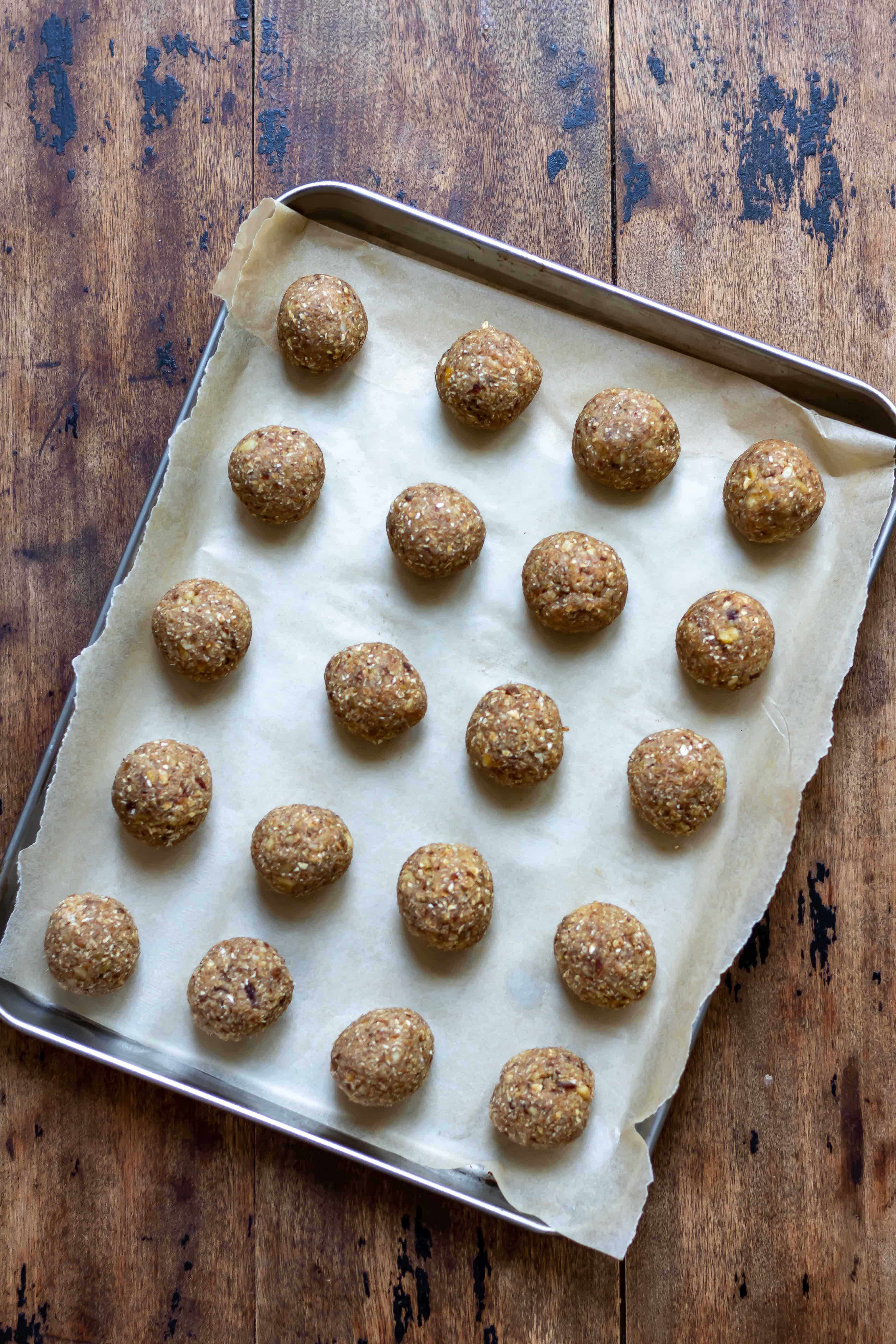 A lined baking sheet with no bake banana bread energy balls on it.