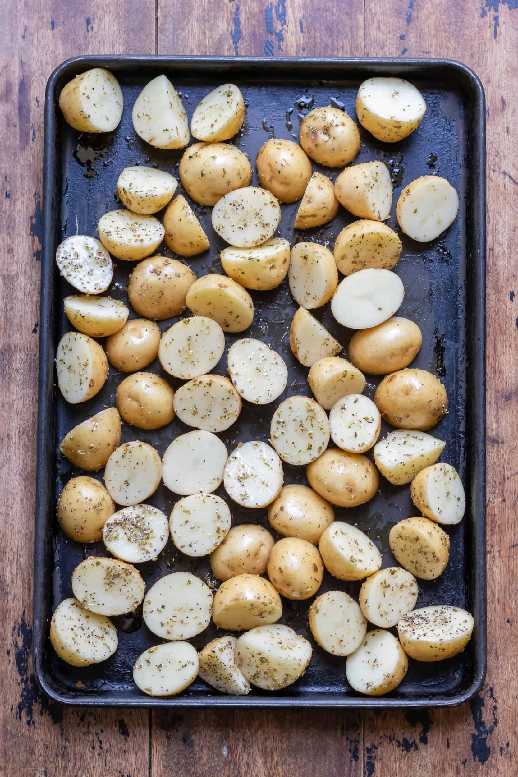 Seasoned Greek potatoes on a baking sheet.