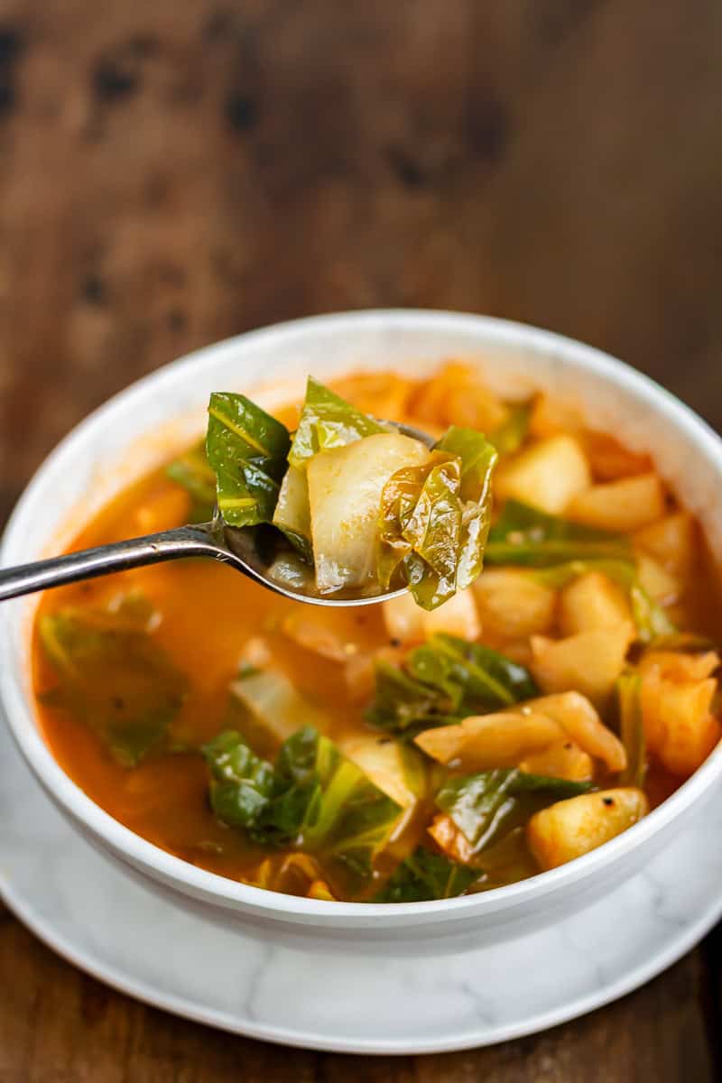 A spoonful coming out of a bowl of weight loss cabbage soup.