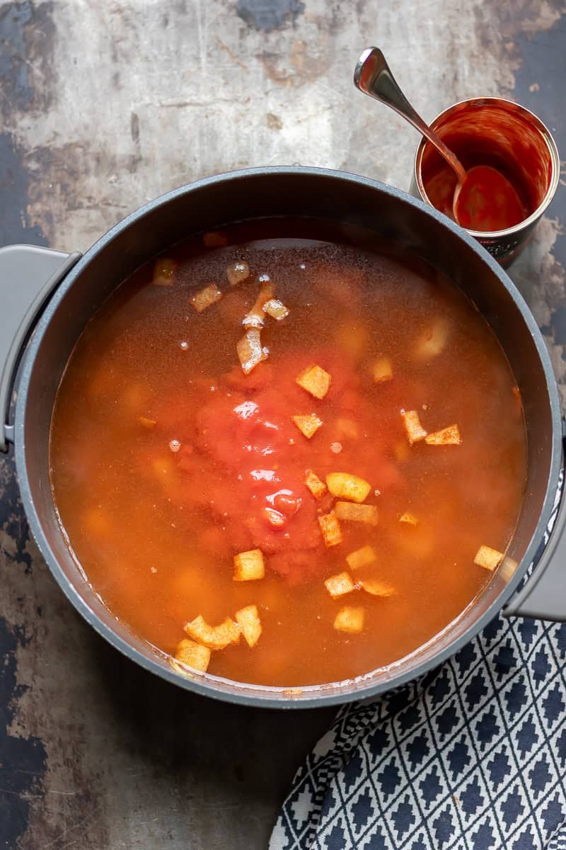 Stock and canned tomatoes added to the pot.