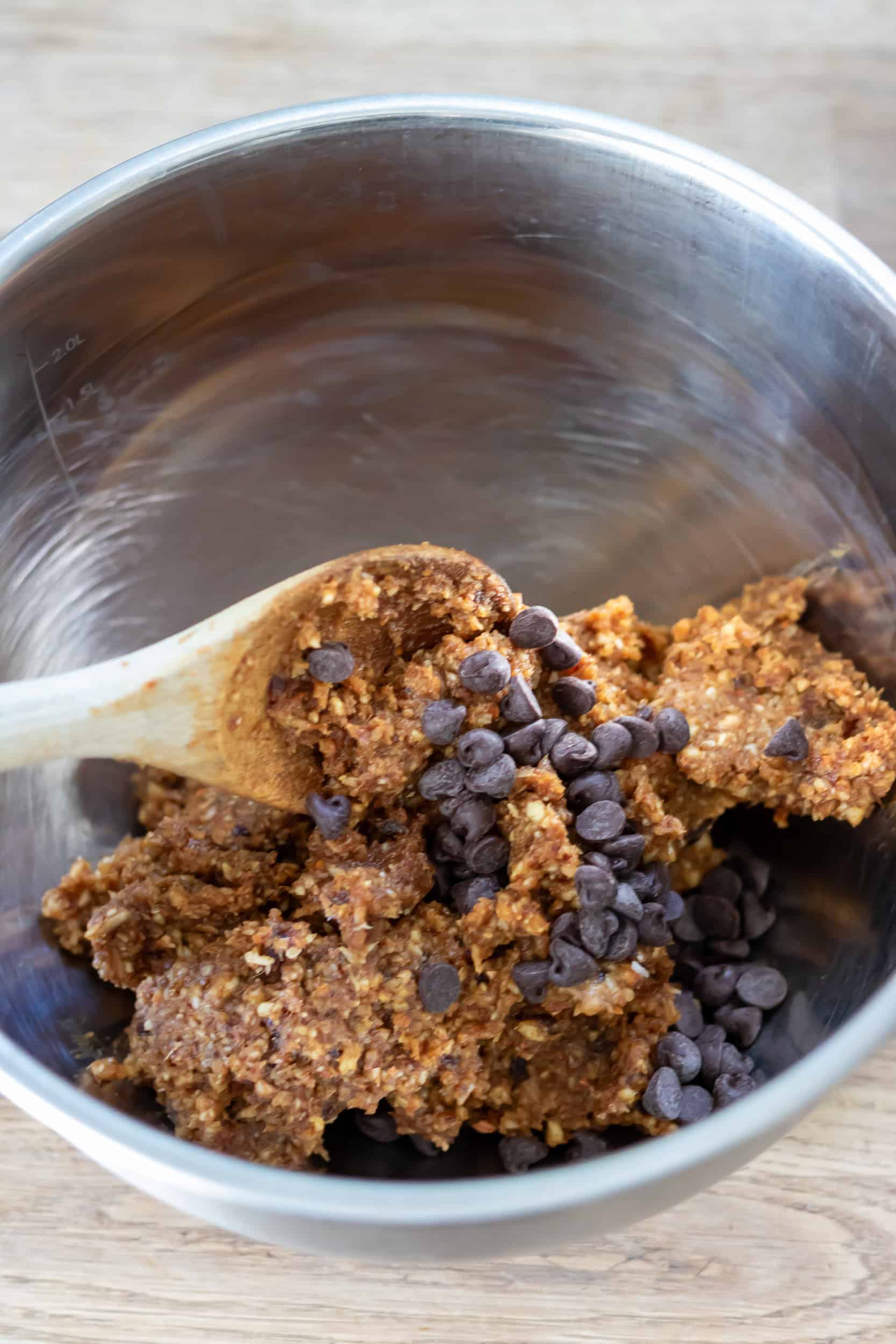 Stirring chocolate chips into the energy ball mixture.