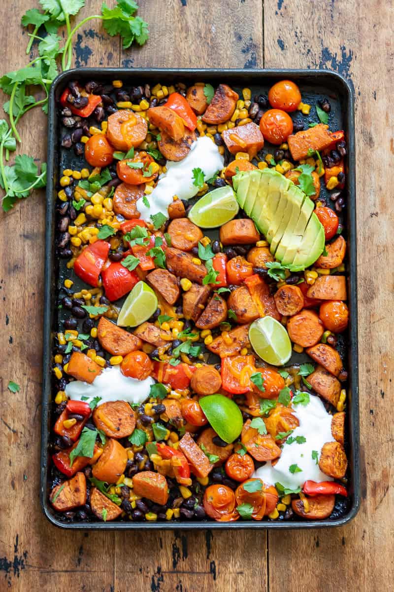 Wooden table with a baking sheet of Mexican Chipotle Sweet Potato and Black Bean bake.
