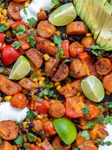 Close up of Mexican Chipotle Sweet Potato and Black Bean bake with limes and avocado.