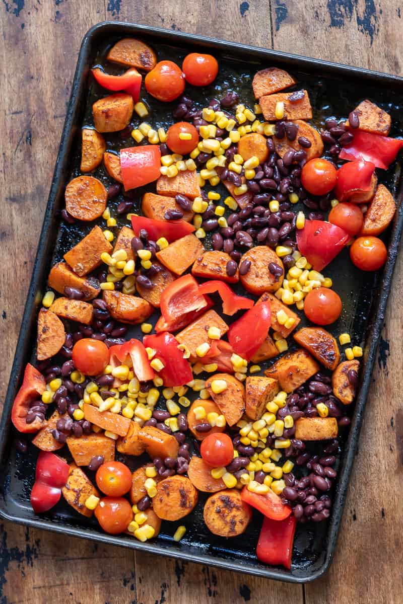 Tomatoes, bell peppers, black beans and corn added to the partially roasted sweet potatoes.