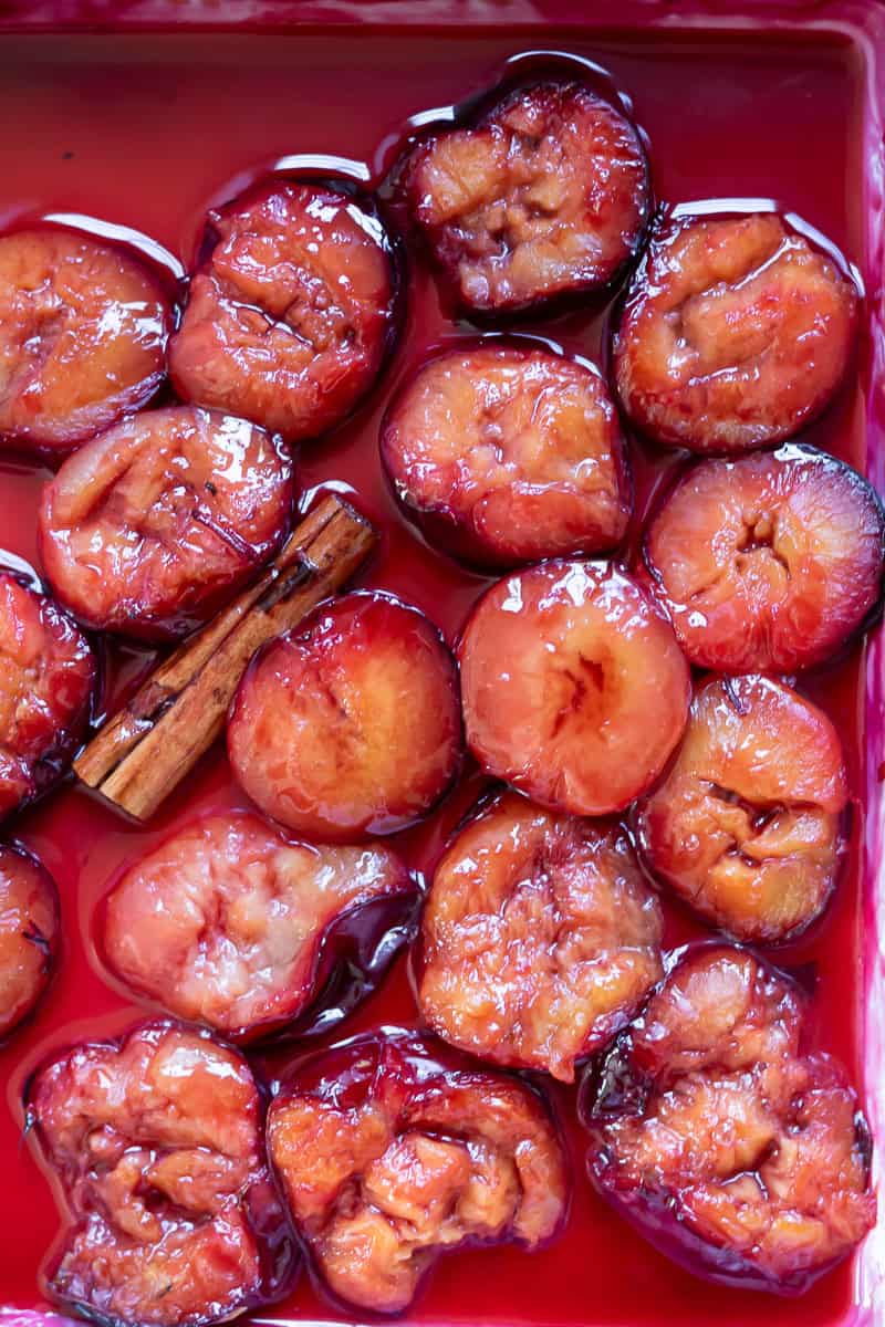 Close up of roasted plums and a cinnamon stick.